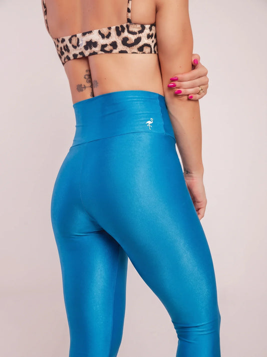 Woman wearing high-waist compression leggings and matching sports bra, mid-stretch in a bright studio
